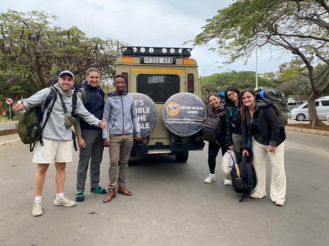 Kakisha guests and their guide in front of a safari vehicle